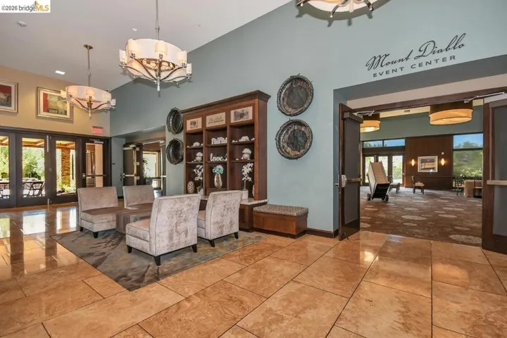 Spacious lobby featuring polished stone tile flooring, high ceilings, built-in shelving, and contemporary pendant lighting