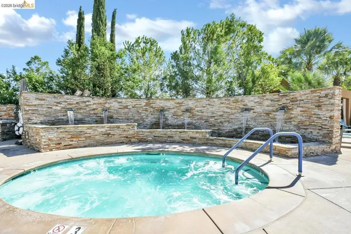 Built-in spa with blue handrails and a stacked stone water feature wall