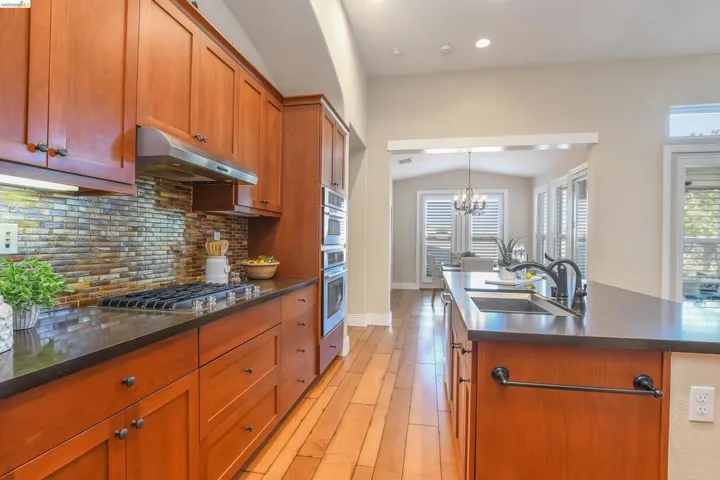 Kitchen featuring wood-finish cabinetry, dark countertops, and a mosaic tile backsplash