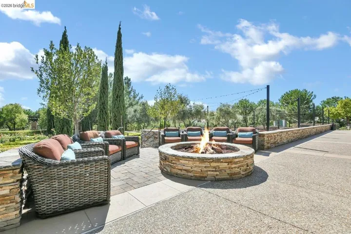 Outdoor patio featuring a stone fire pit, extensive paver and aggregate surfacing, and surrounding stone retaining walls
