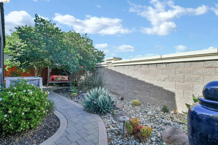 Curved paver pathway bordered by dark gravel and vibrant landscaping