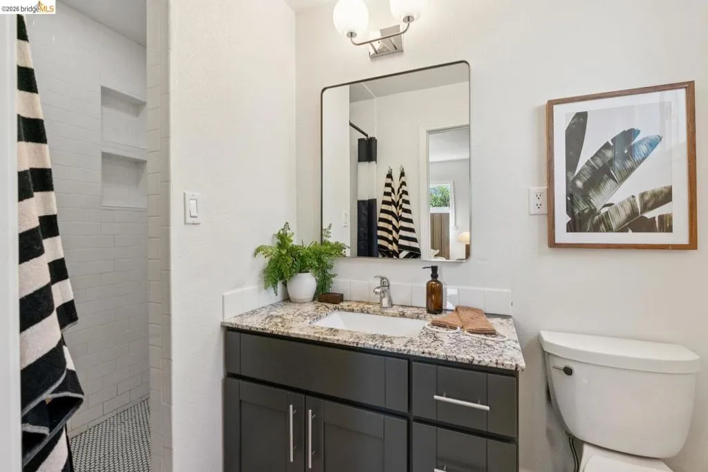 Bathroom featuring a dark wood vanity with a light granite countertop, an undermount sink, and a rectangular framed mirror