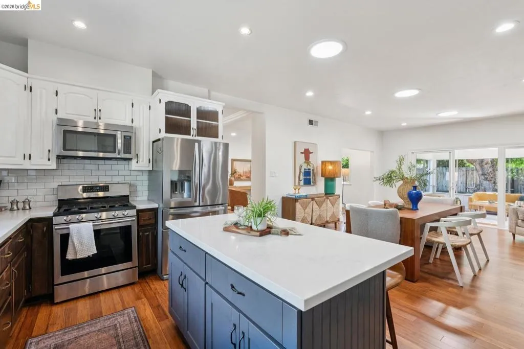 Kitchen featuring a quartz-topped island, stainless steel appliances, subway tile backsplash, and wood-finish flooring