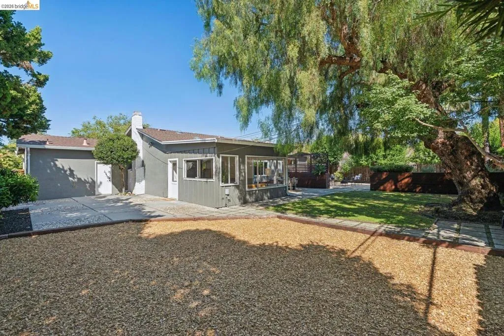 Expansive exterior featuring a gravel patio, green lawn, and mature trees