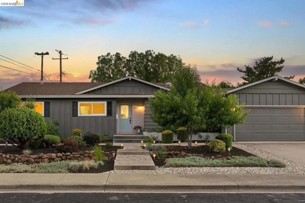 Ranch-style exterior featuring gray siding, a light blue entry door, and a two-car garage