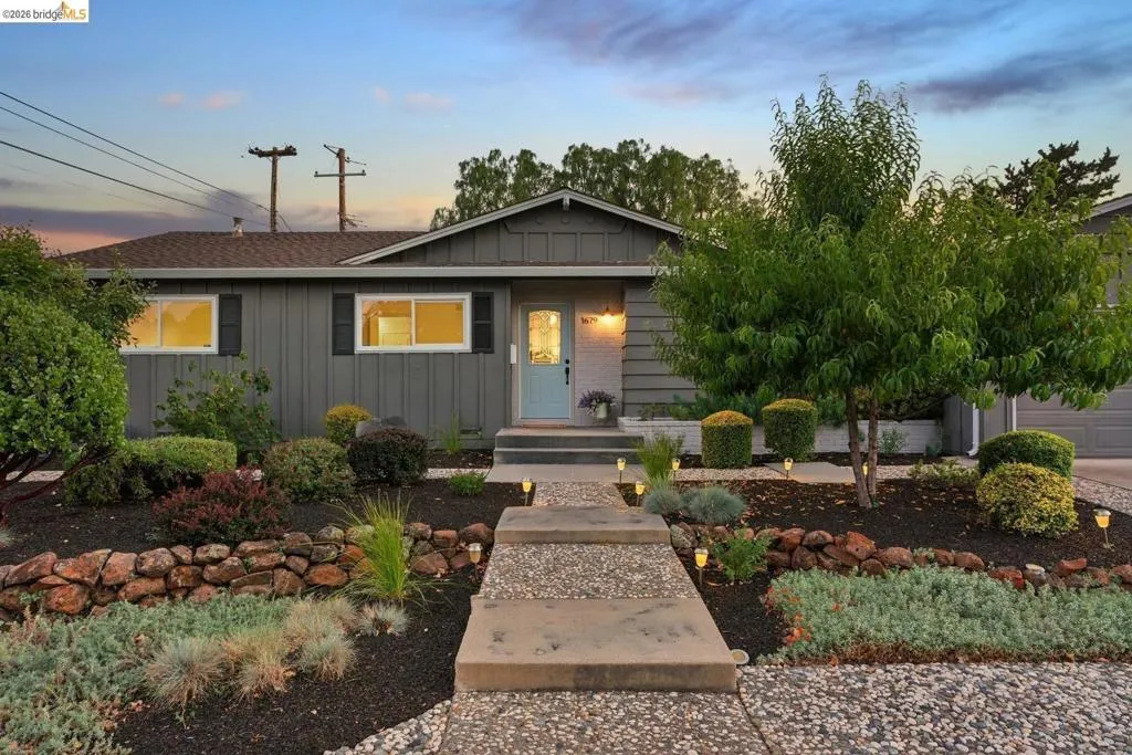 Single-story residence featuring a gray exterior with black window shutters and a light blue entry door