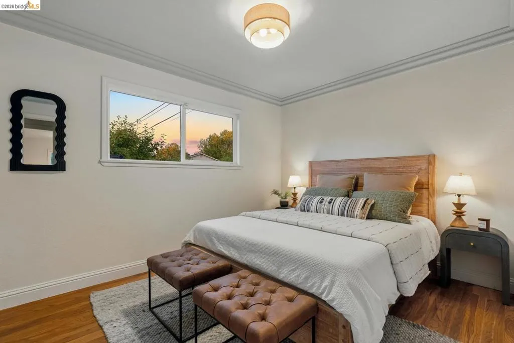 Hardwood-finish flooring complementing light wall tones, crown molding, a flush-mount ceiling light, and a double window