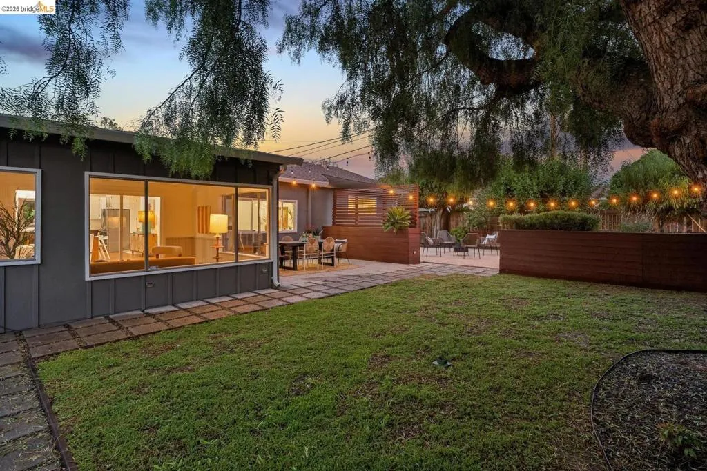 Expansive backyard featuring a manicured lawn, a large paver patio, and mature tree