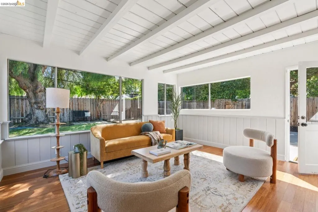 Living area featuring exposed beam ceilings, wood-finish flooring, and large picture windows