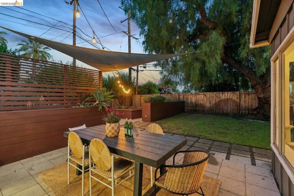 Paved patio area featuring a shade sail and string lighting