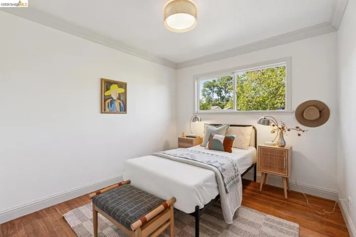 Bedroom featuring wood-finish flooring, a bright window, and crown molding