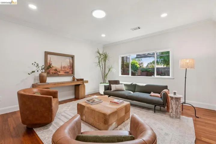Living space featuring wood-finish flooring, a large window, recessed lighting, crown molding, and a skylight