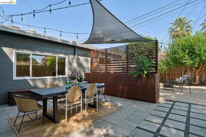 Paved patio area featuring a shade sail and string lighting