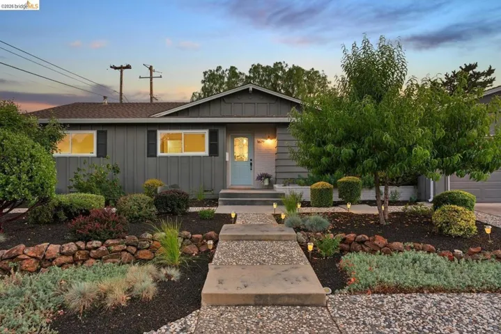 Single-story residence featuring a gray exterior with black window shutters and a light blue entry door