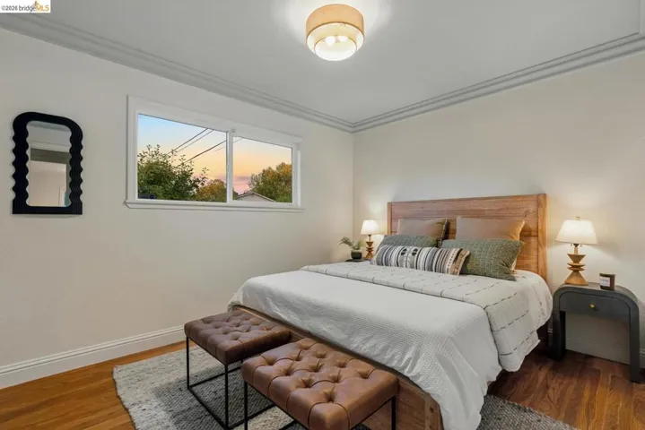 Hardwood-finish flooring complementing light wall tones, crown molding, a flush-mount ceiling light, and a double window