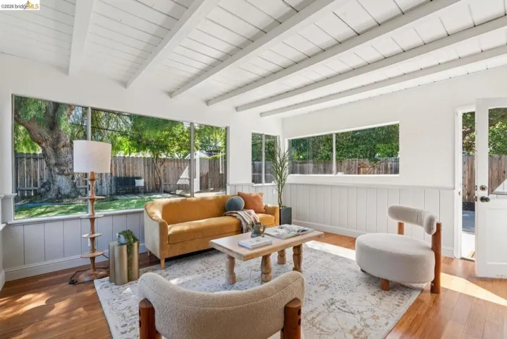 Living area featuring exposed beam ceilings, wood-finish flooring, and large picture windows