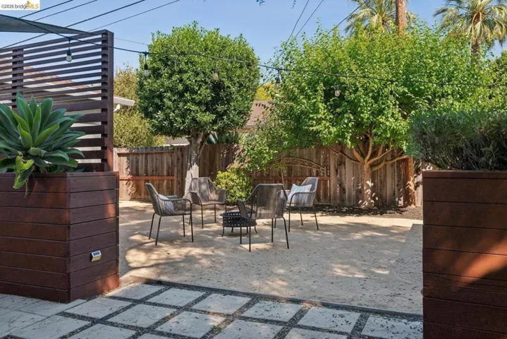 Private outdoor space featuring a large gravel patio, mature trees, and string lighting