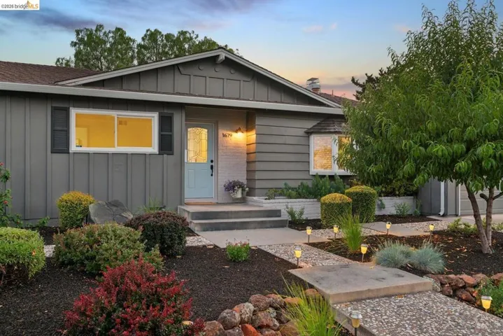 Mid-century modern exterior featuring vertical siding, a light blue entry door with decorative glass, and white window trim