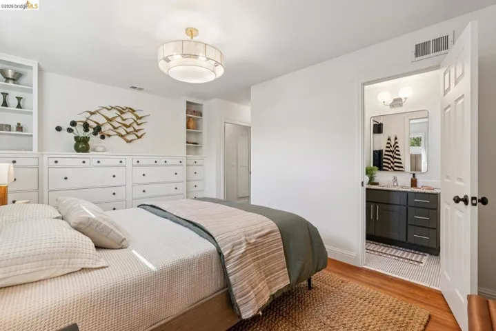 Bedroom featuring built-in cabinetry with integrated drawers, wood-finish flooring, and a contemporary ceiling light fixture