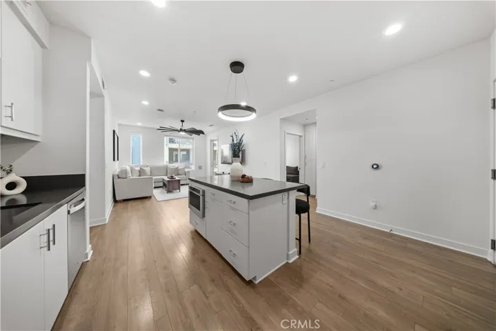 New light fixture over kitchen island and view of beautiful wood flooring throughtout main entry area.