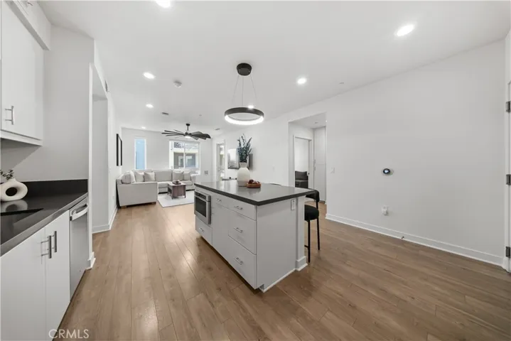 New light fixture over kitchen island and view of beautiful wood flooring throughtout main entry area.