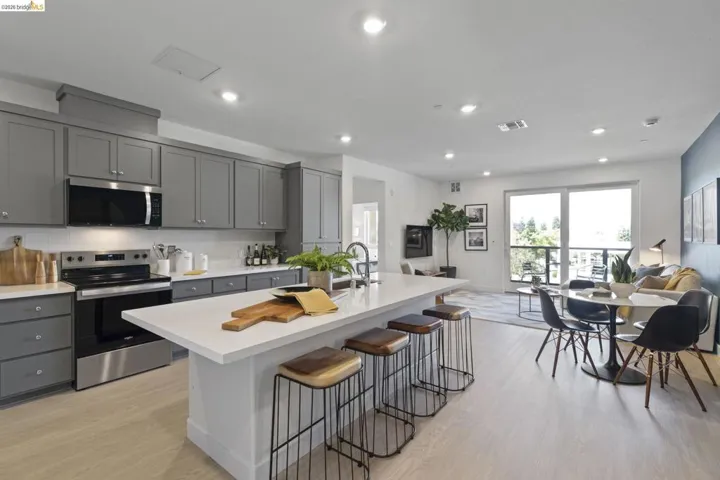 Open-concept living area featuring a kitchen with gray cabinetry, a white subway tile backsplash, and stainless steel appliances