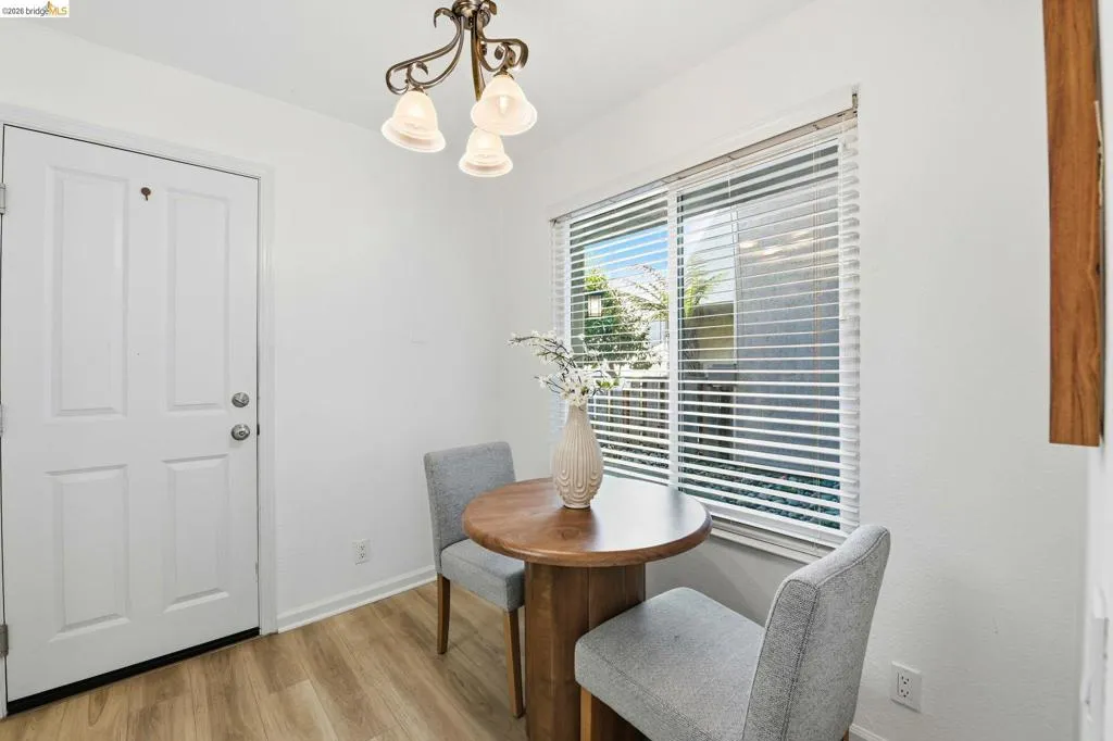 Bright interior featuring white walls, wood-finish flooring, and a multi-pane window with horizontal blinds