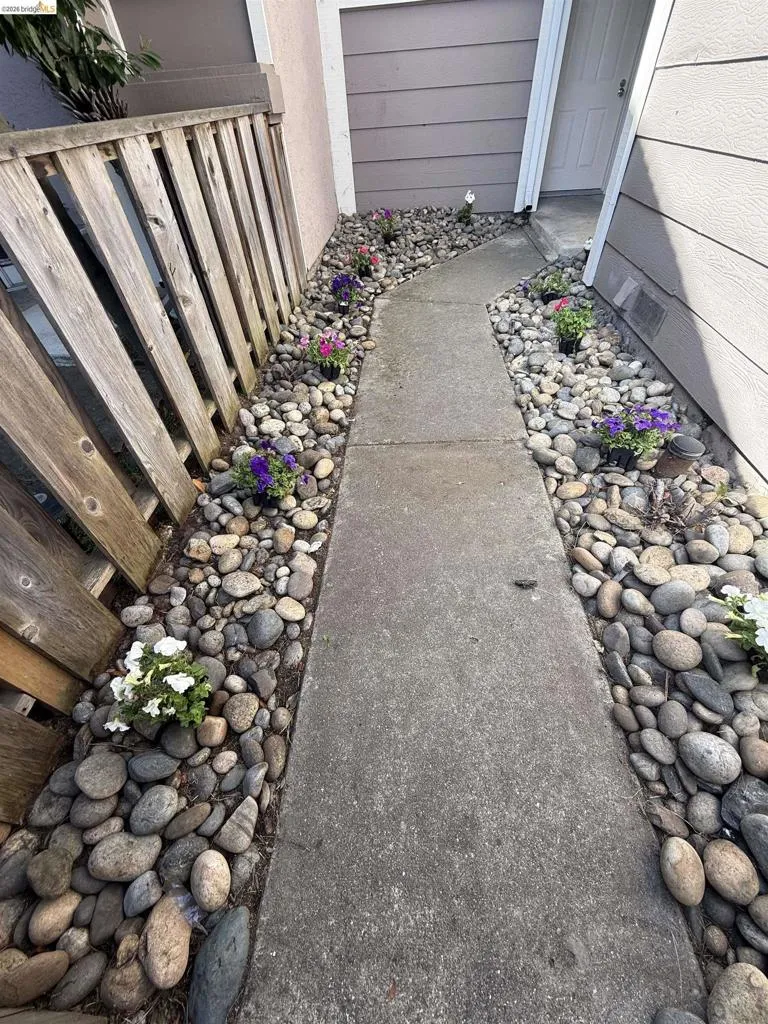 Concrete pathway flanked by river rock landscaping