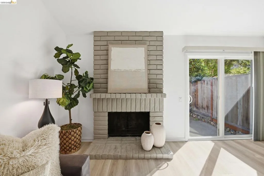 Brick fireplace with a fluted mantel and hearth, wood-finish flooring, and a sliding glass door