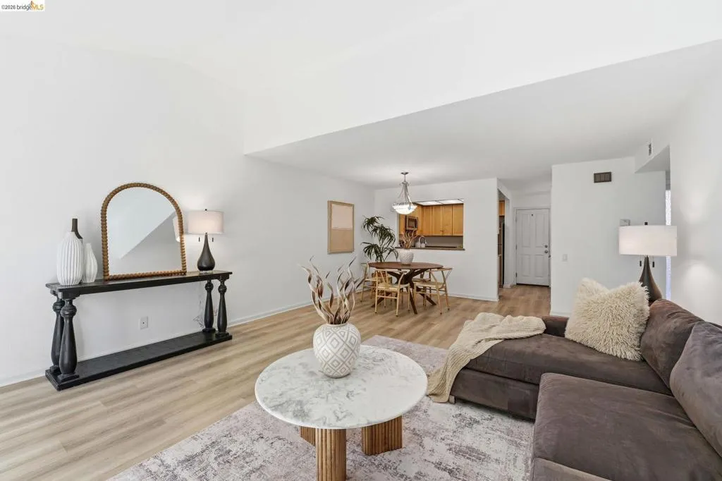 Vaulted ceilings enhance this open-concept living area with light wood-finish flooring