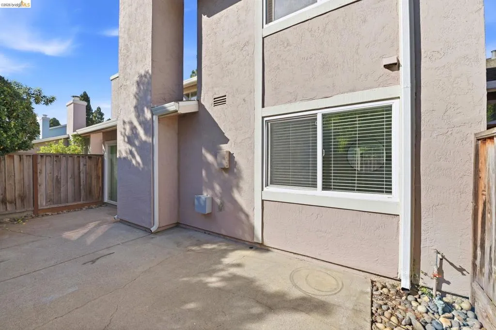 Stucco exterior featuring multiple windows and a sliding glass door