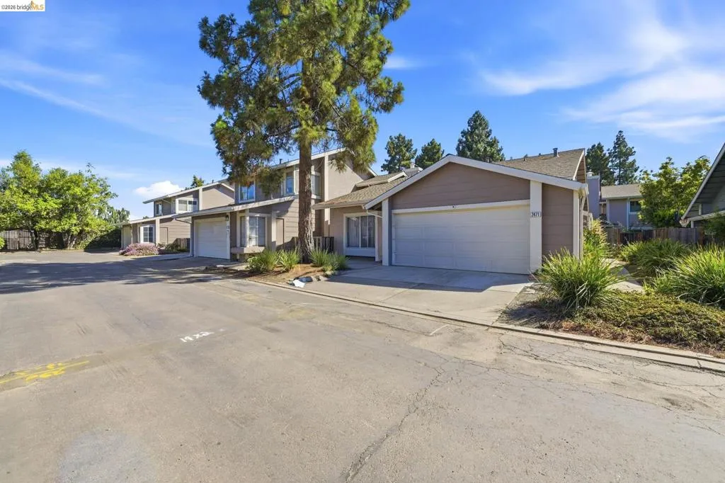 Exterior featuring a two-story design, attached garage, sloped roofline, and mature trees