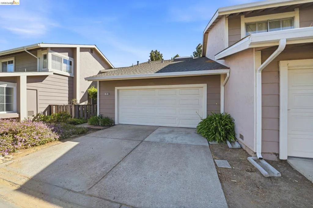 Exterior featuring a two-car garage with a white panel door, stucco and horizontal siding finishes, multiple windows, and a paved driveway