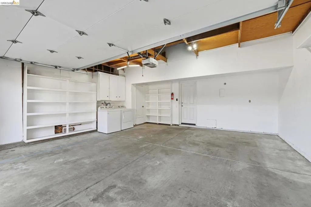 Spacious garage with exposed beam ceiling and concrete flooring