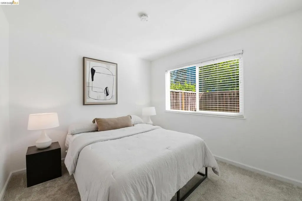 Windowed room featuring light gray carpeting, crisp white walls, and a recessed ceiling light