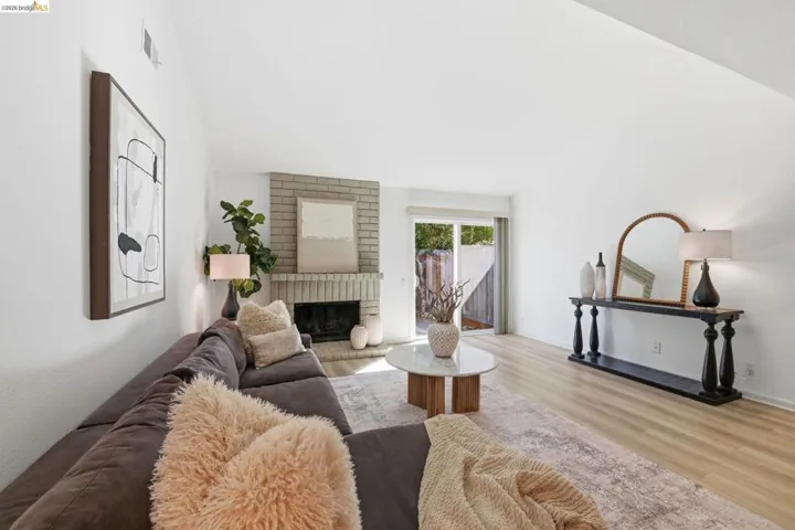 Living space featuring a brick fireplace, vaulted ceiling, and light wood-finish flooring