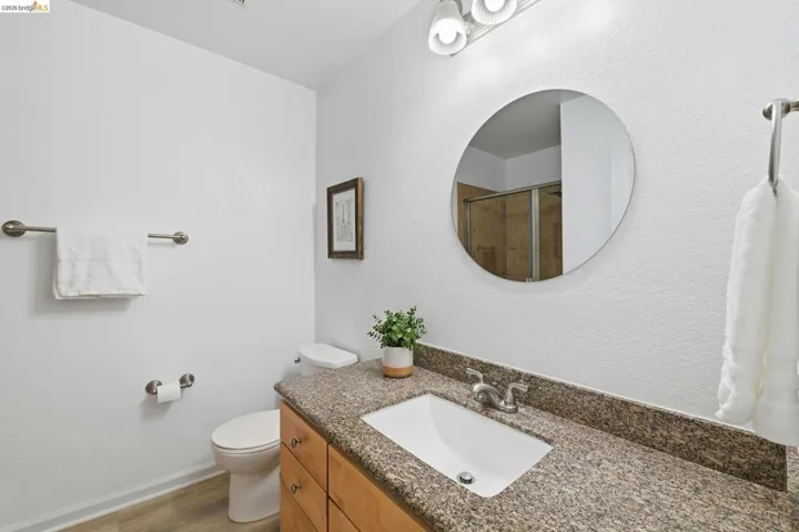 Bathroom vanity with an integrated sink, granite countertop, and light wood-finish cabinetry