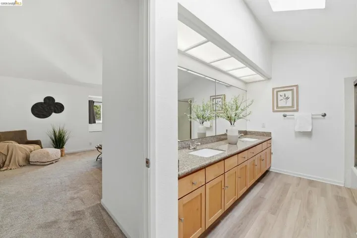 Bathroom featuring a double vanity with stone-finish countertop, light wood cabinetry, and dual undermount sinks