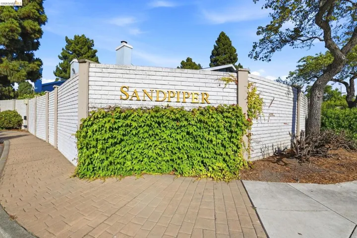 Brick paver walkway leading to a white brick wall with "SANDPIPER" lettering
