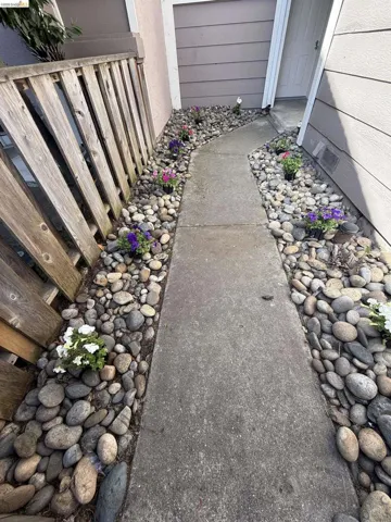 Concrete pathway flanked by river rock landscaping
