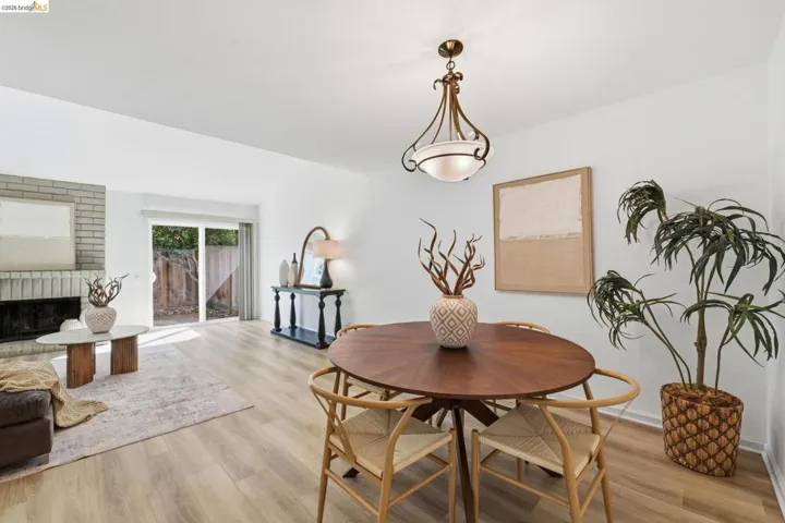 Open-concept living space featuring wood-finish flooring, a brick fireplace, and direct access to outdoor space via a sliding glass door