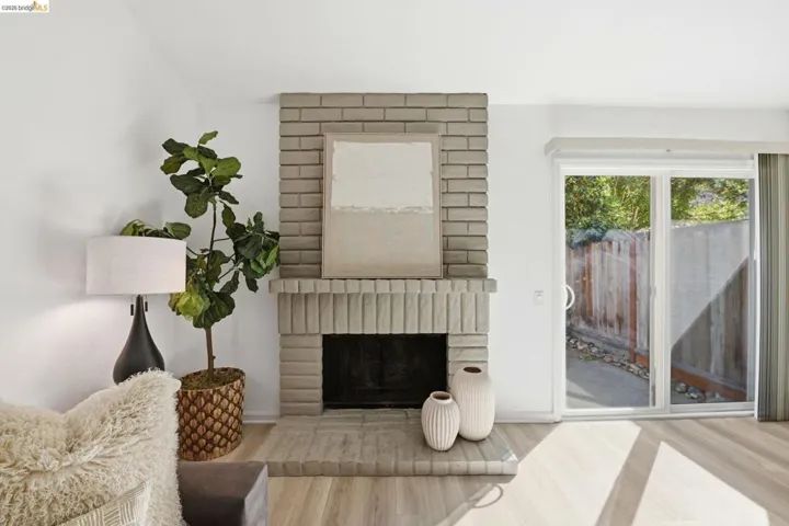 Brick fireplace with a fluted mantel and hearth, wood-finish flooring, and a sliding glass door