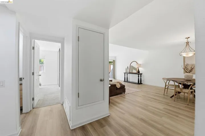 Open-concept living space with wood-finish flooring, white walls, and a dedicated dining area featuring an overhead chandelier