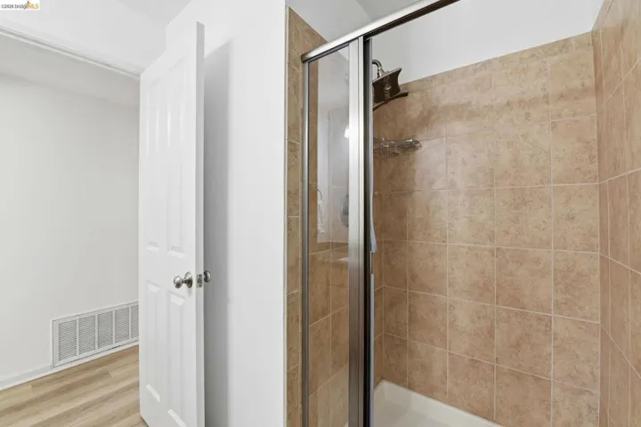Full-height tiled shower enclosure with sliding glass door and integrated showerhead