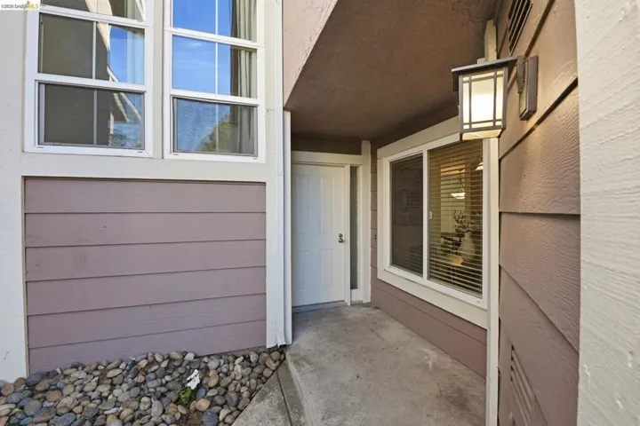 Entryway featuring a white door, concrete pathway, and a decorative wall lantern