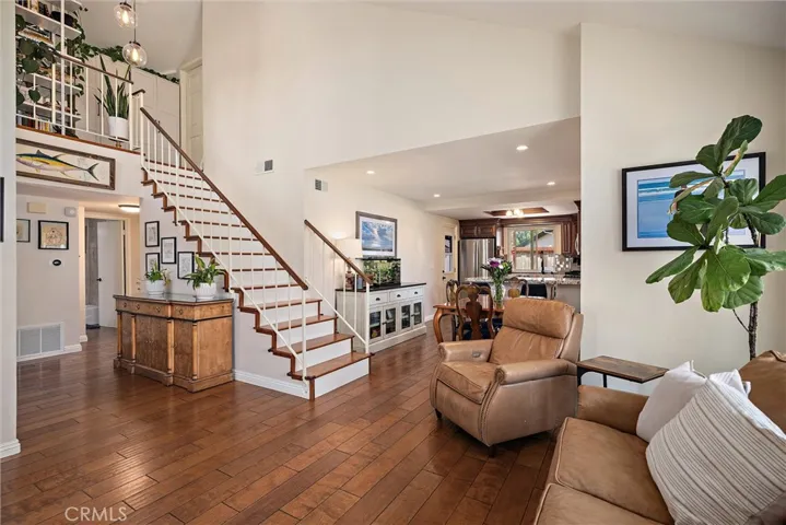Expansive and spanning shot of the hardwood floors, beautiful globe/sconce fixture at entry and open floor plan.