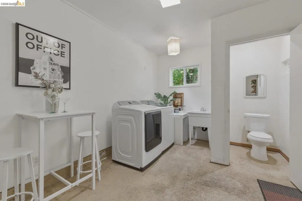Dedicated utility room featuring a window, laundry sink, and a separate half-bath