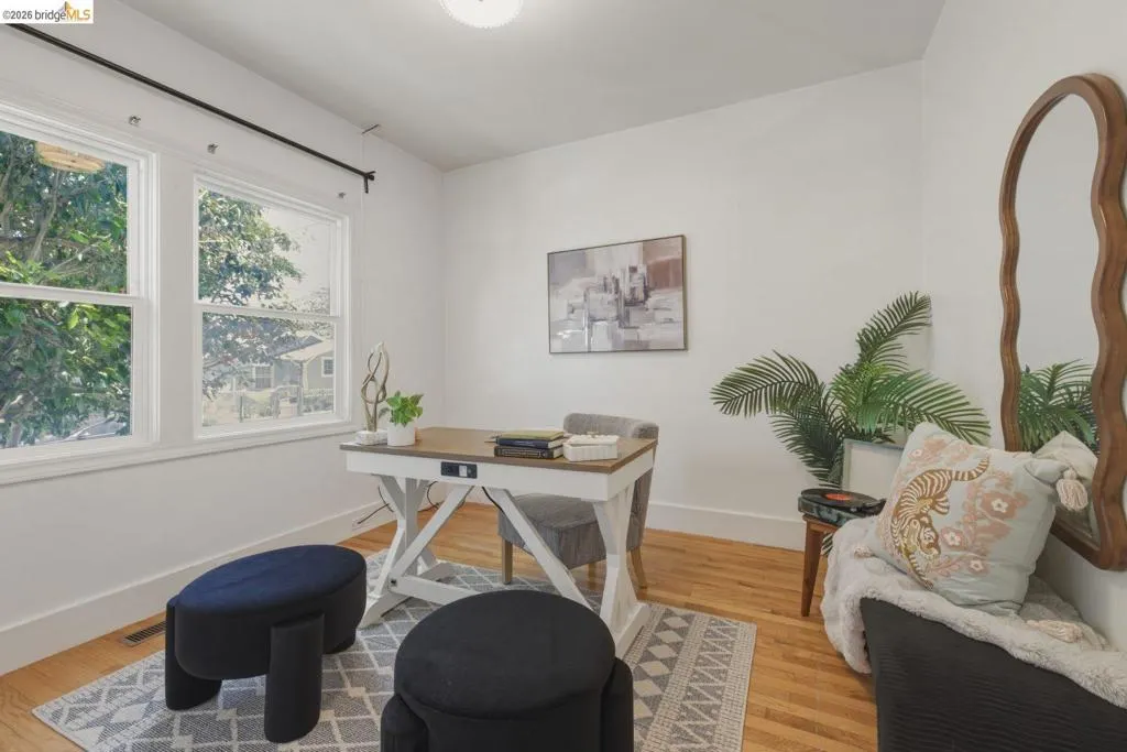 Bright room featuring two large windows, wood-finish flooring, white walls, and a patterned area rug