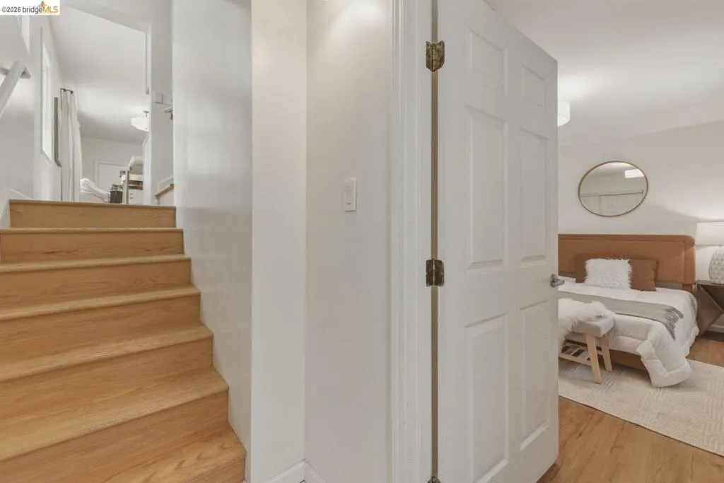 Wood-finish stair treads with white risers ascend to an upper level