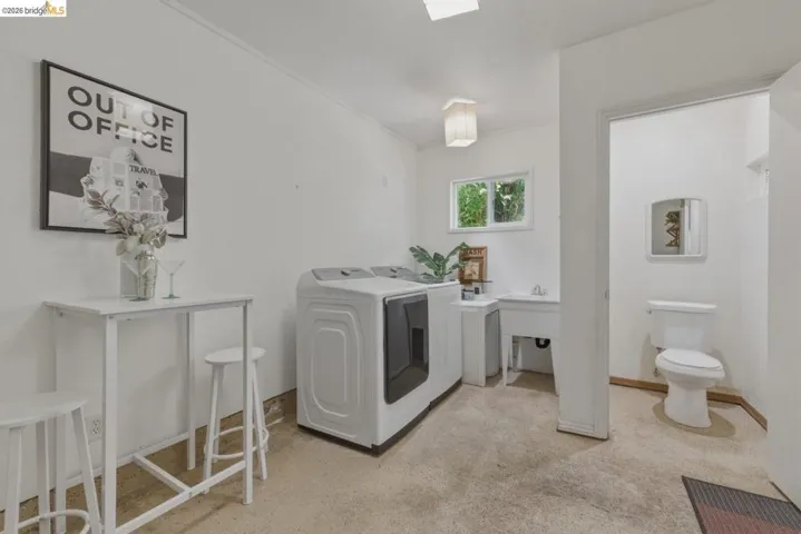 Dedicated utility room featuring a window, laundry sink, and a separate half-bath